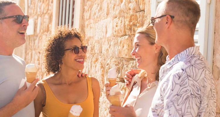 Grupo de viajeros riendo y comiendo helado en un callejón de piedra iluminado por el sol de Dubrovnik.