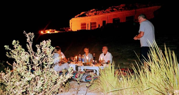 Personas cenando en un lugar al aire libre iluminado por lámparas.