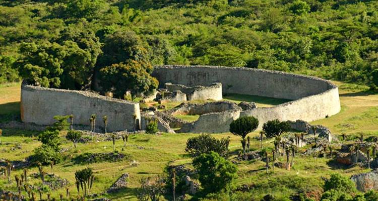 Ruins of an ancient stone structure surrounded by greenery.