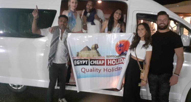 Groupe de personnes tenant une bannière touristique avec un véhicule en arrière-plan.