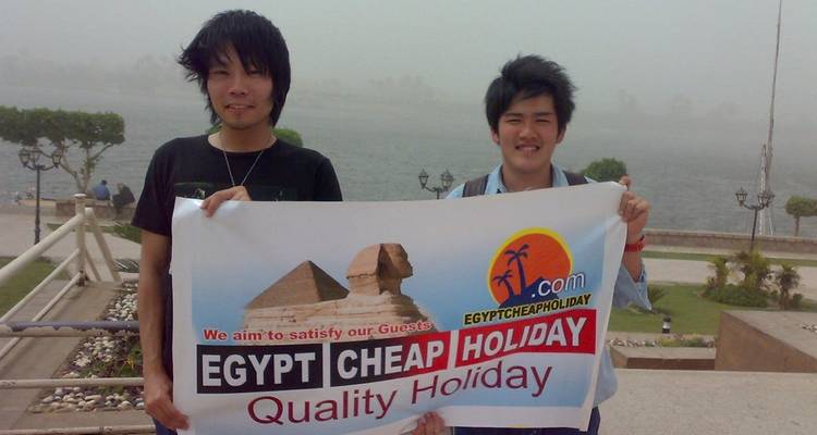 Deux personnes tenant une banderole avec les Pyramides et le Sphinx en arrière-plan.