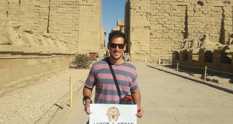 Personne avec un panneau de voyage devant des ruines antiques.