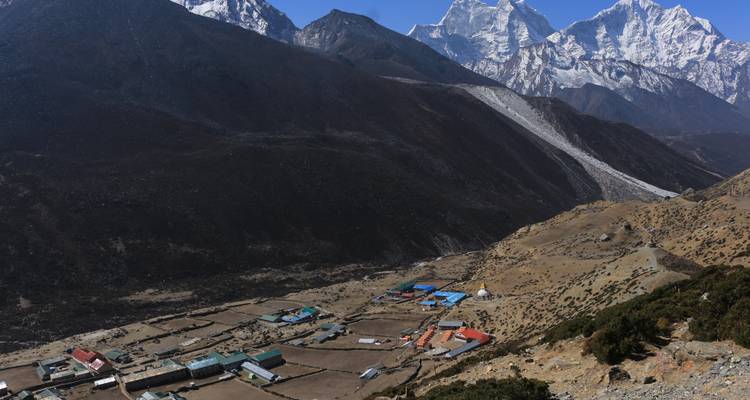 A small village in the mountains with a glacier and snowy peaks.