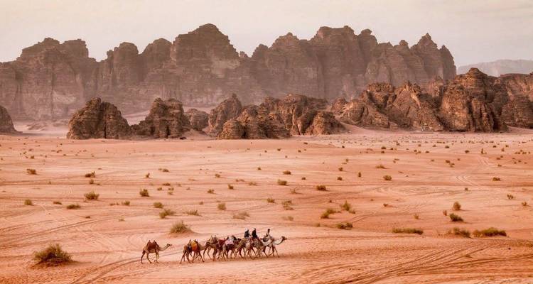 People riding camels in a desert scenery.