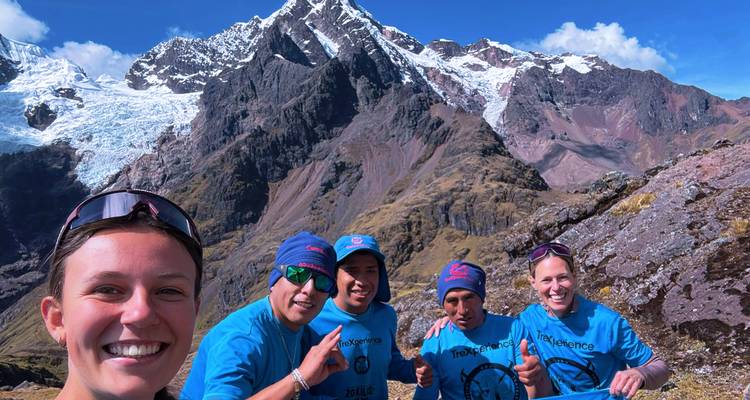 Groupe de personnes posant avec des montagnes en arrière-plan.