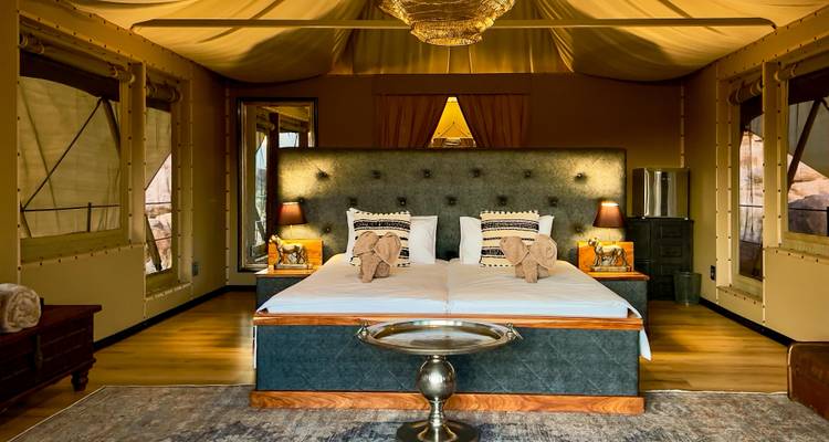 Luxurious tent interior with a large bed and elegant decor.