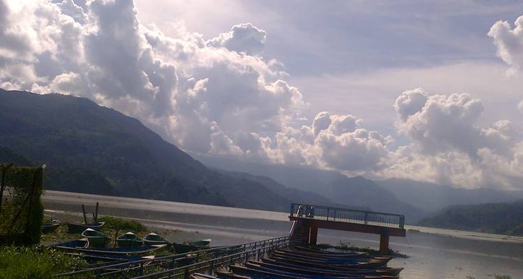 Malerische Aussicht auf einen See mit Booten und Bergen im Hintergrund.