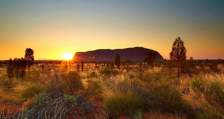 Zonsopgang boven Uluru met een prachtige waaier van kleuren die het woestijnlandschap verlicht.