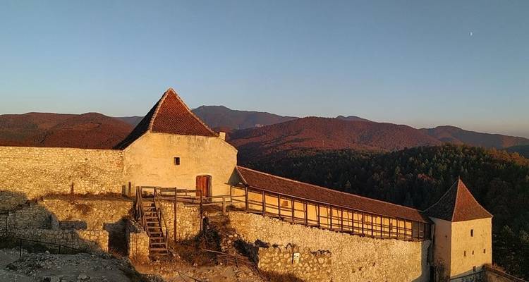 Un fort historique avec un arrière-plan montagneux au coucher du soleil.