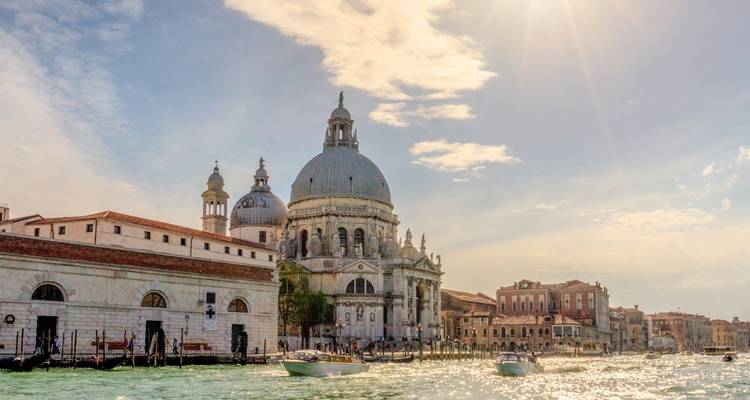 A grand cathedral by a canal in Venice with gondolas in the water.