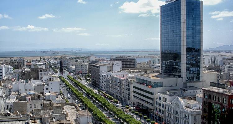 Paisaje urbano con un edificio moderno alto y una vista de calle amplia.