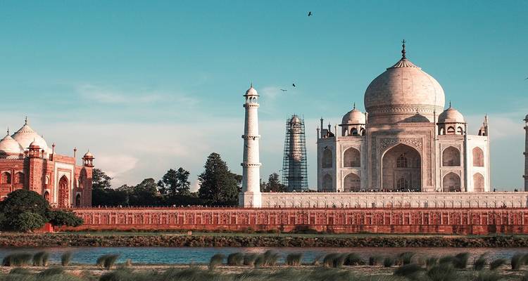 Vista lateral del Taj Mahal con cielo azul despejado.