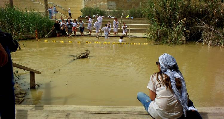 Des gens rassemblés au bord d'une rivière boueuse ayant une importance historique.