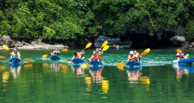 Kajakkers peddelen op een kalme smaragdgroene rivier omringd door bos.