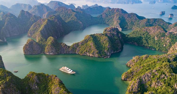 Een luchtfoto van Halong Bay met een cruiseschip en kalksteenformaties.