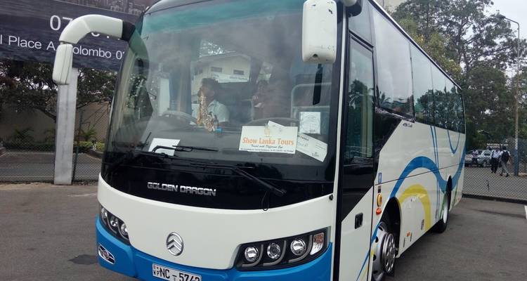 Autobus de tourisme garé à un dépôt avec des passagers visibles à travers le pare-brise