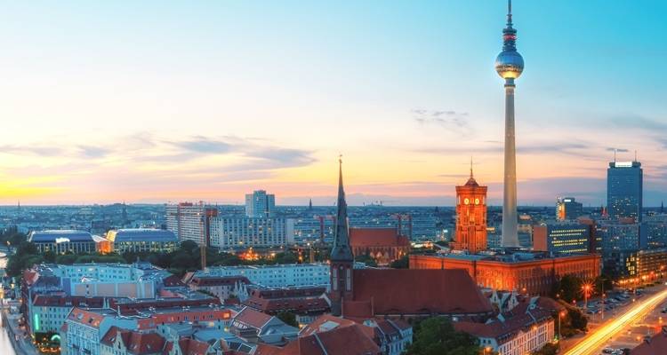 Horizon de Berlin au coucher du soleil avec la tour de télévision Fernsehturm et les toits historiques illuminés par la lumière du soir.