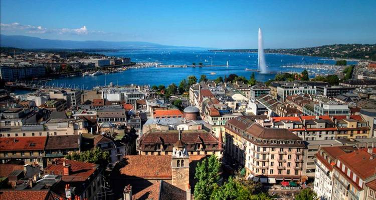 Geneva cityscape with the Jet d’Eau fountain shooting skyward from Lake Geneva on a clear day.