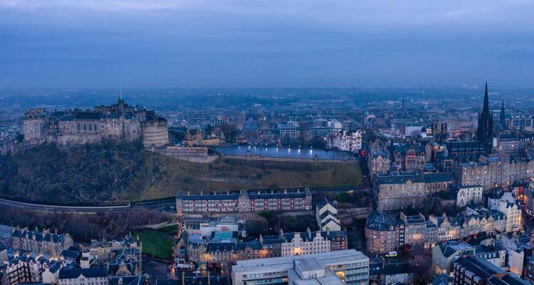 Panoramisch uitzicht van Edinburgh tijdens het blauwe uur met het kasteel en stadsverlichting