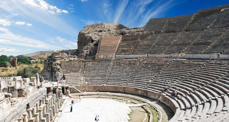 Antikes steinernes Amphitheater mit aufragenden Sitzplatzstufen unter einem dramatischen Himmel.
