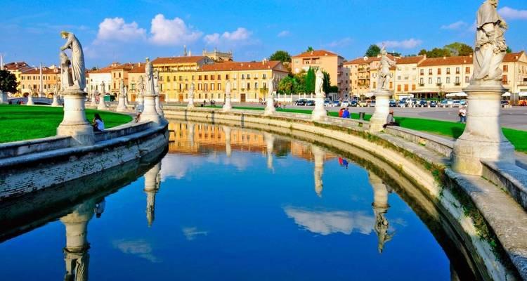 Gekrümmter Kanal der Prato della Valle in Padua, gesäumt von Statuen, die sich perfekt im stillen Wasser spiegeln.