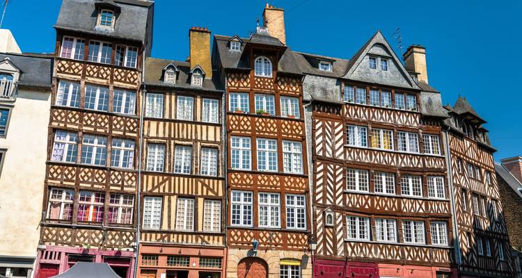 Rangée de maisons médiévales à colombages colorées se dressant côte à côte contre un ciel bleu clair.