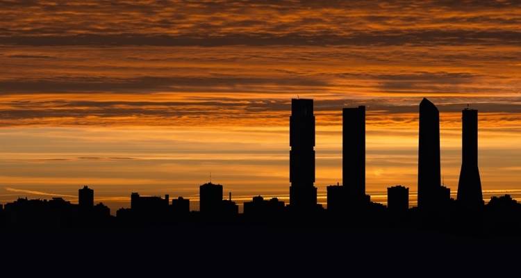 Ciel doré de coucher de soleil au-dessus de la silhouette assombrie des plus hautes tours de Madrid.