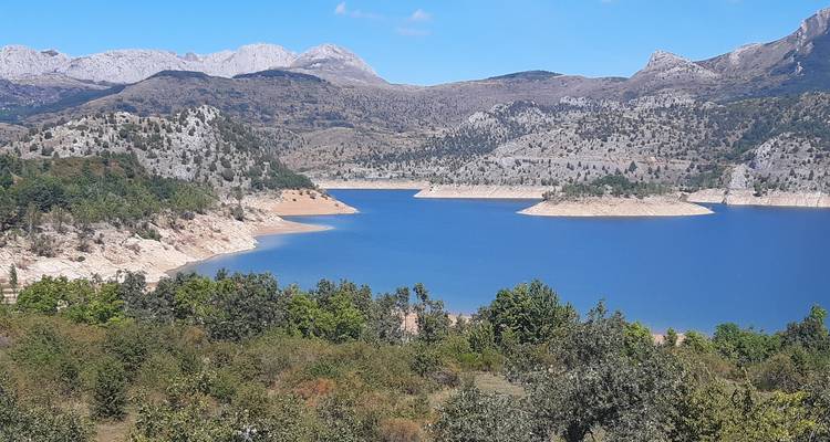 Un lac bleu naturel avec un terrain accidenté environnant et de la verdure.