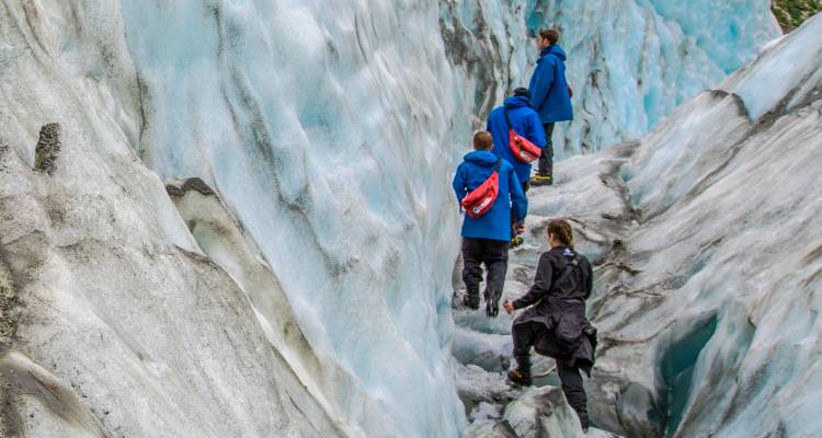 People walking on a glacier wearing climbing gear.