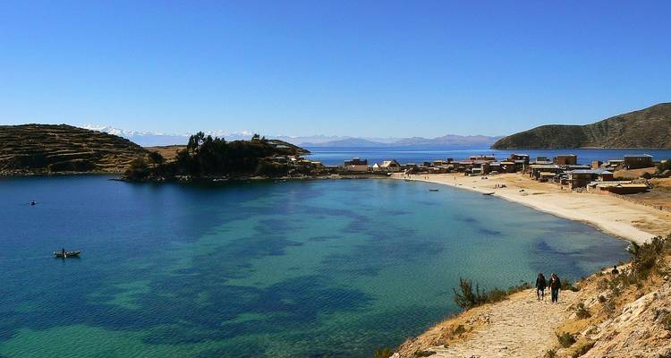 Lac avec un village et des montagnes en arrière-plan.