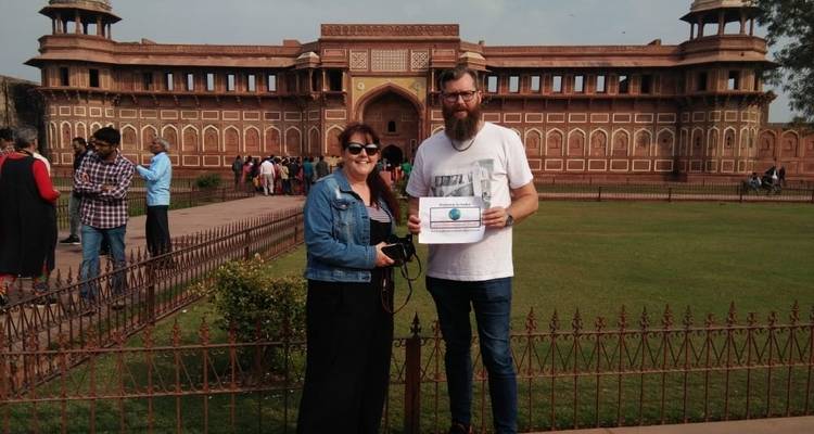 Twee mensen die een bord vasthouden voor een fort in India.