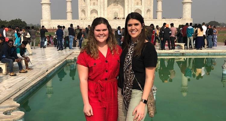 Twee mensen die poseren voor de Taj Mahal met een menigte op de achtergrond.