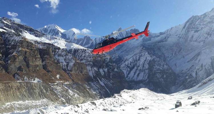 Helicopter flying over snow-capped mountains.