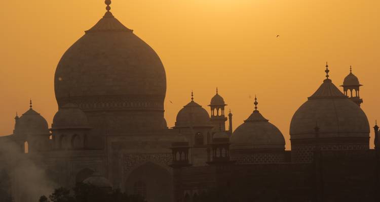 Silhouette du Taj Mahal sur un ciel de coucher de soleil orange.