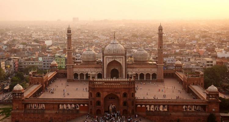 Luchtfoto van Jama Masjid bij zonsondergang met een druk stadslandschap.