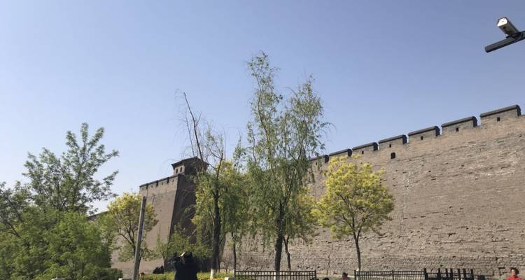 Mur de forteresse en brique avec des arbres et un ciel dégagé.