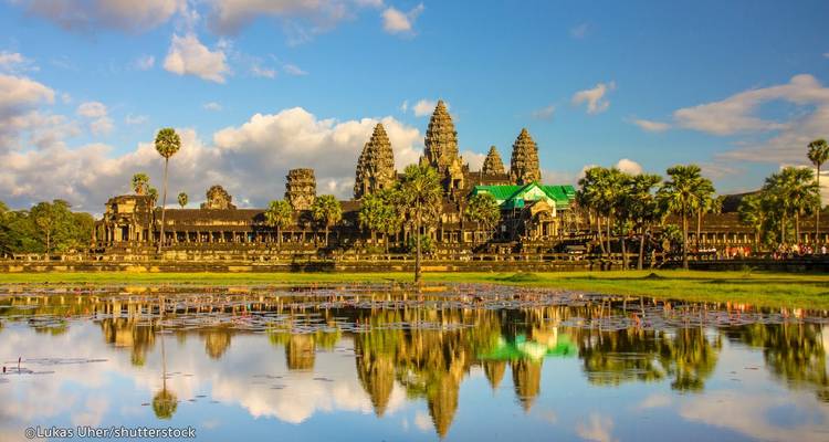 Temple d'Angkor Vat avec reflet dans l'eau et ciel bleu.