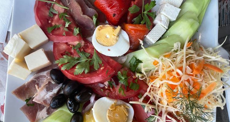 Plat bulgare coloré avec tomates, fromage, œufs, olives et salade.