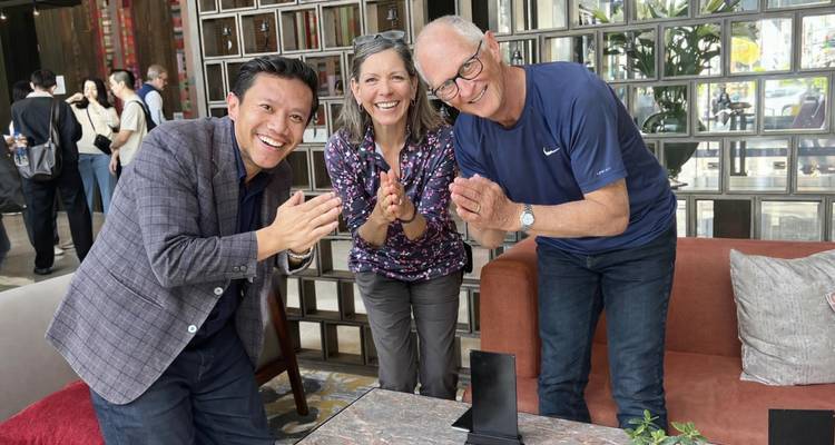 Tres personas aplaudiendo y sonriendo en interiores.
