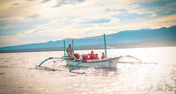 A group on a traditional outrigged boat on a scenic lake.