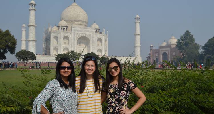 Trois personnes devant le Taj Mahal avec les jardins environnants.