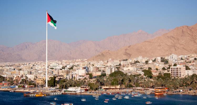 Vue panoramique de la ville et du port d'Aqaba avec le drapeau jordanien géant et les montagnes arides