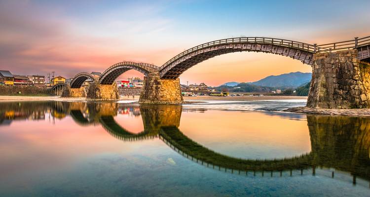 Le magnifique pont Kintai aux multiples arches se reflétant sur la rivière calme lors d'un coucher de soleil coloré.