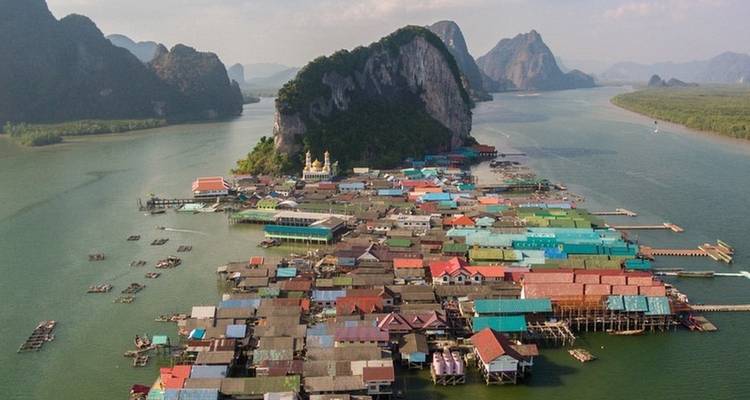 Aerial view of village by the water with mountains in the background.