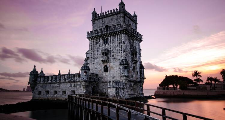 Torre histórica junto al río al atardecer.