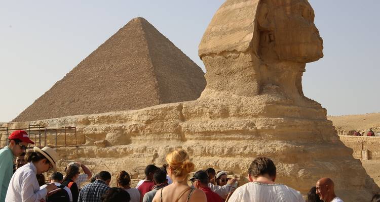 The Sphinx with the Great Pyramid in the background, surrounded by tourists.