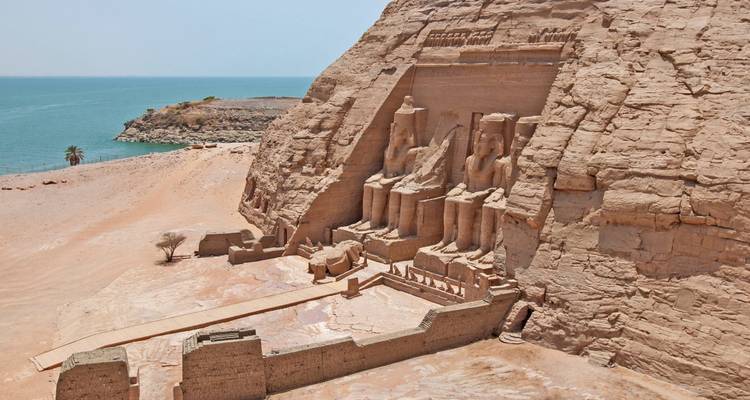 Abu Simbel temples carved into a rock cliff by the water.