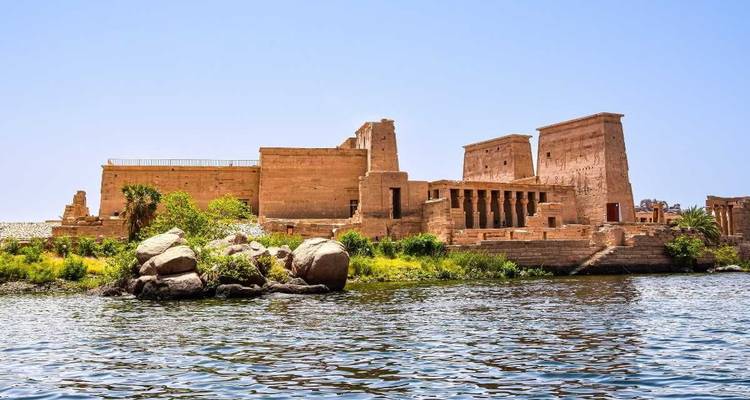 Ancient temple by the river surrounded by greenery.