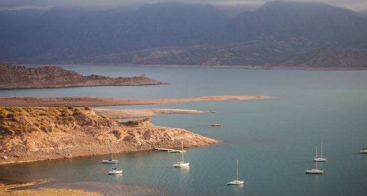 Una vista panorámica de un lago con veleros y colinas circundantes.