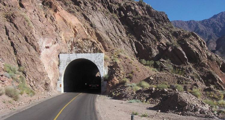 Entrada de túnel de montaña con acantilados rocosos.